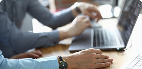 Two persons using laptops in an office environment